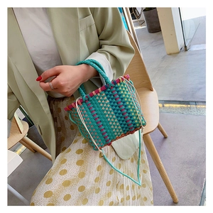 Detail van kleurrijke geweven handtas met trekkoordsluiting en turquoise handvat