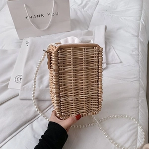 Détail du sac seau en paille tissée avec bandoulière perlée et doublure intérieure blanche
