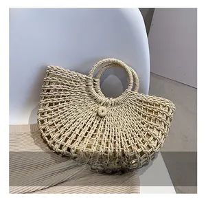 Detail view of the hollow-out woven texture and circular handle of this straw beach bag
