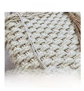 Detail shot of handwoven straw bag featuring decorative tassels and natural textures