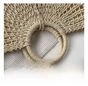Detail shot of the sturdy circular handle and openwork woven texture of the straw bag