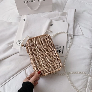 Détail du petit sac carré en paille tressée à la main avec bandoulière perle élégante