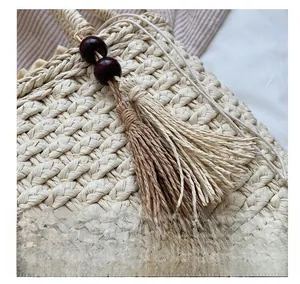 Detail of woven straw bag with wooden beads and two-tone tassels hanging on the side