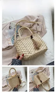 Detail view of beige woven straw tote with decorative wood bead tassels and drawstring