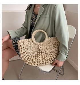 Detailed close-up of handmade hollow straw handbag with woven ring handles and soft fabric lining