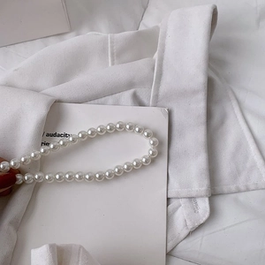 Gros plan sur l'élégante poignée en perles blanches d'un sac de plage en paille tissé