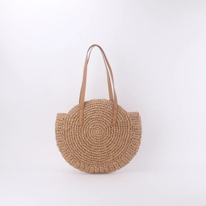 Detail of round straw bag with reinforced leather handles and woven texture