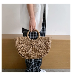 Detail of the hollow woven pattern and round handles on a half-moon straw tote bag