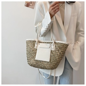 Detail of woven straw tote bag with white leather trim and metal rivets for women