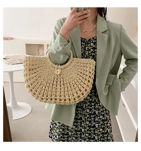 Detail of hollow-out beige straw tote bag with circular handles for summer beach vacations