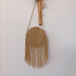 Detail of round woven straw bag with long fringe tassels and handmade crochet texture