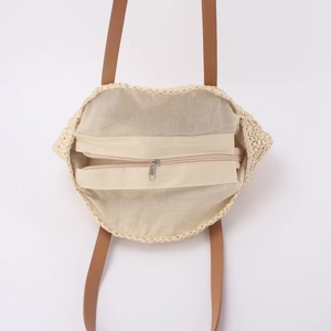 Minimalist round woven straw tote bag with brown leather handles and zipper closure