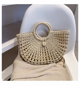 Close-up of beige woven straw tote bag with intricate hollow mesh texture and round handles