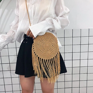 Detail of round straw bag with long fringe tassels and handmade woven texture