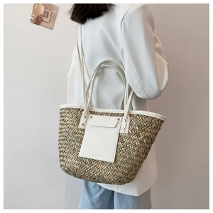 Detail of hand-woven straw tote bag with white leather pocket and metal rivets