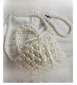 Détail du sac à main en perles crème avec nœud en soie blanche et bandoulière perlée