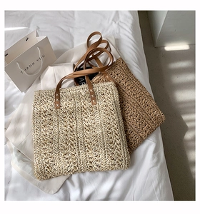 Detail of woven straw tote bags with leather handles and intricate stitch texture
