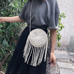 Detail of cream round woven crossbody bag with long tassels and thin shoulder strap