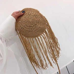 Detail of round crochet woven bag featuring long tassels and bohemian fringe texture