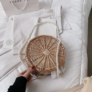 Détail du sac rond en paille avec texture tressée et grande anse en perles élégante
