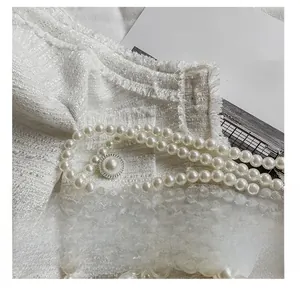 Détail du tissu en tweed blanc avec bandoulière en perles et bouton texturé argenté