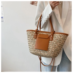 Detail of woven straw tote bag featuring caramel leather trim and functional front pocket