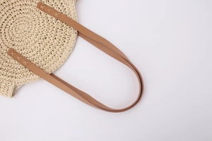 Detailed view of round straw bag with spiral weaving and brown leather handles