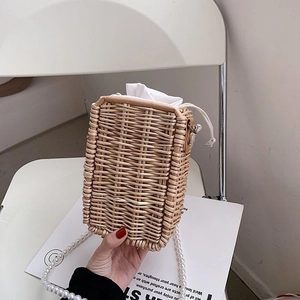 Détail d'un sac en paille tissé avec chaîne en perles et doublure à cordon blanc