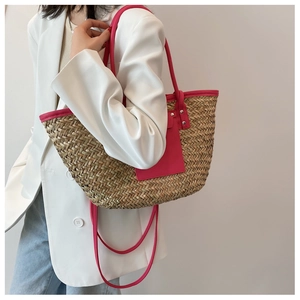 Detail of hand-woven straw tote with vibrant pink leather pocket and slim handles