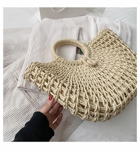 Close-up of beige straw tote bag with intricate hollow weave and soft fabric lining