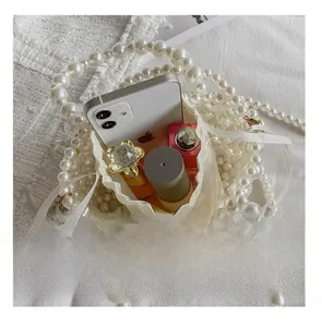 Détail de capacité du sac perlé contenant téléphone, rouge à lèvres et parfum
