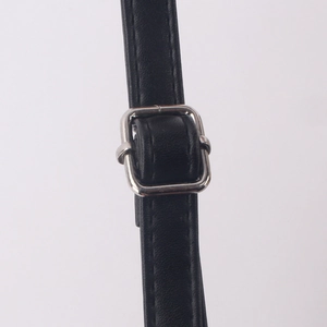 Vue macro d'une bandoulière en cuir noir avec une boucle de réglage rectangulaire argentée