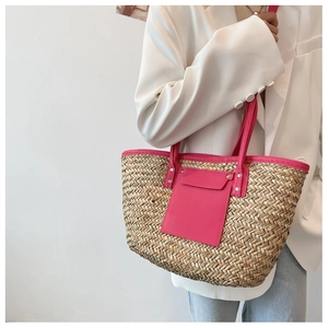 Detail of hand-woven straw tote with vibrant pink handles and trim on white outfit