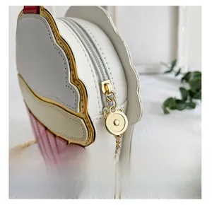 Close-up of a cupcake-shaped handbag featuring a smooth golden zipper and pink striped texture