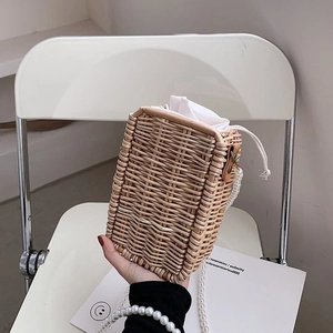 Détail d'un sac en paille tressée avec bandoulière en perles blanches et doublure en tissu