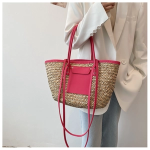 Detail view of woven straw tote bag with vibrant pink leather trim and top handles