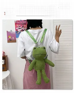 Détail d'un sac à dos grenouille en peluche verte avec texte Cute frog sur la sangle