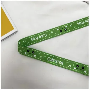 Détail de la bandoulière en nylon vert avec imprimé grenouille et texture de tissu réglable
