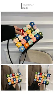 Close-up of handmade crochet bag with colorful floral knit pattern and black shoulder strap