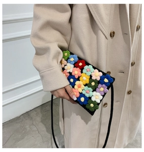 Detailed view of handmade black crochet bag with colorful 3D knitted flower patterns
