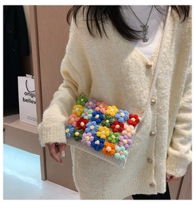 Detail of hand-crocheted shoulder bag with colorful 3D knitted flowers on white cotton