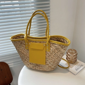 Straw tote bag with bright yellow leather handles and front pocket for summer travel