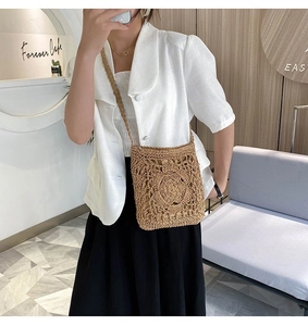 Detail of hand-woven straw crossbody bag with floral cut-out pattern and rustic texture