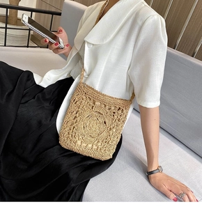Detail of a beige handmade straw crossbody bag with floral hollow weave pattern