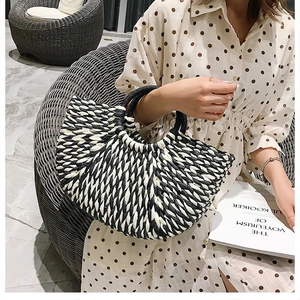 Detail of fan-shaped black and white woven straw handbag with circular dual handles