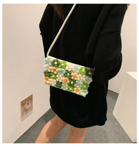Detail of colorful 3D knitted floral crossbody bag worn by a model in a minimalist setting
