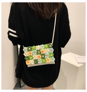 Detail of hand-crocheted floral crossbody bag featuring colorful 3D knitted flowers
