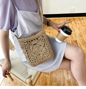 Detail of light brown straw crossbody bag with central 3D crochet flower decoration