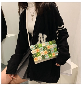 Detail of hand-woven floral crossbody bag with colorful crochet flowers on white knit