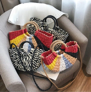 Detail of woven straw tote bags with colorful stripes and sturdy handles on a sofa